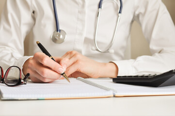 a doctor writes down information with a pen in a diary