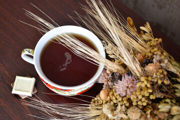 Wildflowers and a cup of black tea with white chocolate. Spikelets over the mug. View from above.