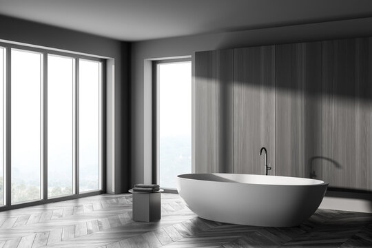 Corner Interior of modern bathroom with grey wooden walls, concrete floor, comfortable white bathtub.