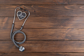 Workplace of a doctor. Stethoscope and little heart on wooden desk background
