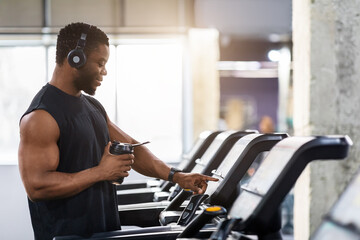 Muscular african american man with protein drink standing on treadmill