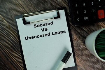 Secured Vs Unsecured Loans write on a paperwork isolated on Wooden Table.