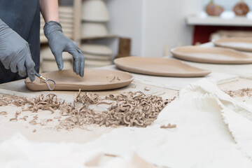 hands of person making pottery plates, working with clay in ceramic workshop