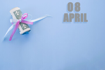 calendar date on blue background with rolled up dollar bills pinned by blue and pink ribbon with copy space. April 8 is the eighth day of the month