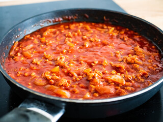 Pork minced meat frying in pan with tomato sauce 
