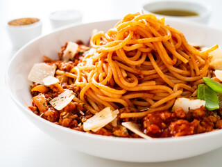 Spaghetti bolognese with minced pork meat and parmesan on white background