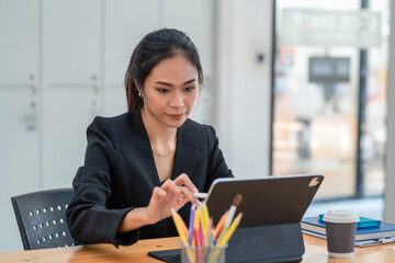 Young Asian businesswoman are busy working on a tablet at the office.
