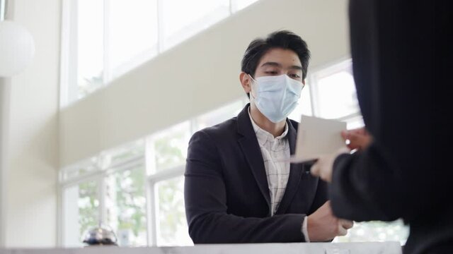 Asian Businessman Connect With Travel Receptionist In Airport Lounge. Telephone Operator To Check Hotel Room Reserve. Mask And Face Shield To Prevent COVID-19 Infection. Concept Service Business