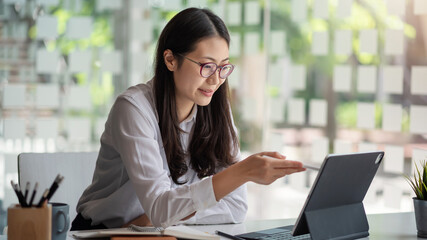 Young Asian businesswoman is happy to work at the modern office using a tablet.