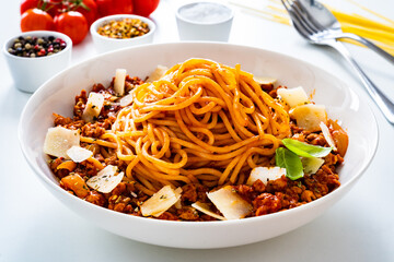 Spaghetti bolognese with minced pork meat and parmesan on white background