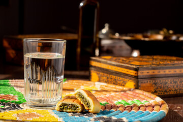 Arabic sweets, maamoul and water on traditional background