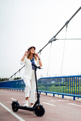 Cheerful woman wearing helmet while standing with electric push scooter during sunny day © Miguel Lifestyle