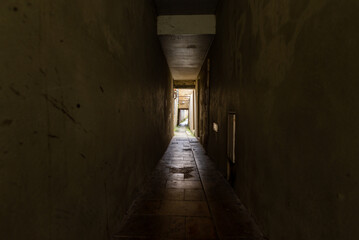 A dark, spooky corridor leading to a lit area