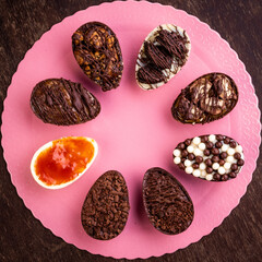Mini stuffed chocolate easter eggs on a pink stand on a wooden table.