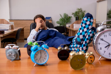 Young male employee sleeping in the office in time management co