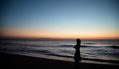 Fototapeta premium girl has a glass of wine in front of the sea at sunset