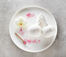 Spa composition with Herbal massage balls and white orchid, flat lay, top view, on gray concrete background
