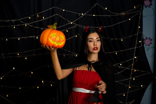 Caucasian beautiful woman fortune teller in red witch costume standing on black background