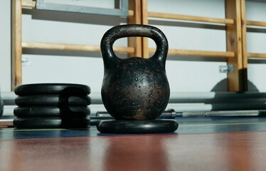 Naklejka na ściany i meble Black kettlebell exercise for weight lifting on the background of the monkey bar in the gym. Accessories for sports and healthy lifestyle.