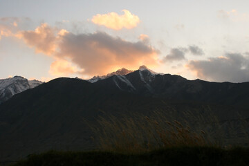 Obraz na płótnie Canvas A bright orange sunset over sharp black Pamir mountains in the shade