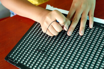 Center for blind children run by Children Action.  Girl writing braille.  Ho Chi Minh city. Vietnam.  11.08.2017