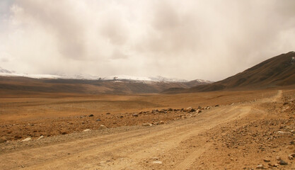 Pamir Highway in the desert landscape of the Pamir Mountains in Tajikistan. Afghanistan is on the left