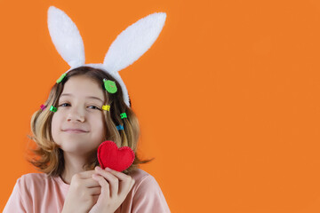 beautiful girl with cute face and bunny ears on her head with knitted heart in her hands on colorful bright background