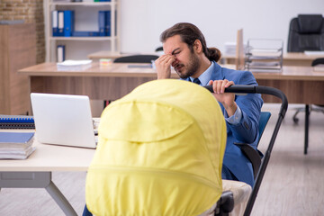 Young male employee looking after new born at workplace