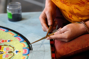 Obraz premium Tibetan monk working on sand mandala. Close-up. France. 25.02.2017