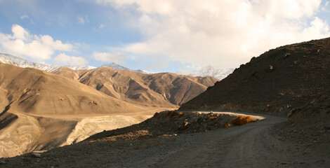Pamir Highway in Gorno-Badakhshan Autonomous Region, Tajikistan. Deep Central Asia. Rocks, Blue Sly and Clouds. Untouched Nature in the Centre of Earth. Snow covered Pamir mountains.