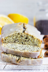 Lemon cake with poppy seeds, covered with glaze on a light background.