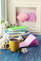 Cup of hot coffee, blank notebook, books, spring flowers on the windowsill, home learning concept, seasonal greetings