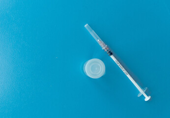 Naklejka premium flatly with syringe, ampoules with vaccine, medical mask and gloves on a blue background