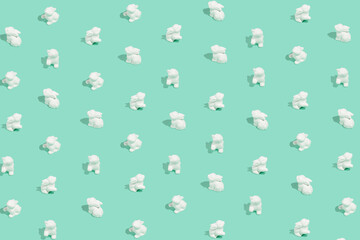 Easter pattern composition made of white easter bunnies on pastel background. Minimal holiday concept