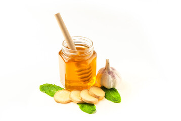 Glass jar of honey with ginger, mint and lemon isolated on a white background