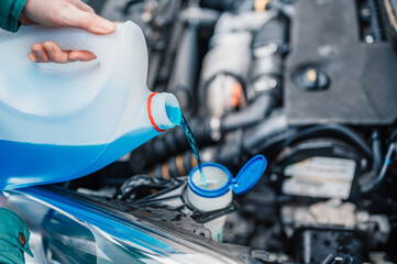 Pouring antifreeze. Filling a windshield washer tank with an antifreeze in winter cold weather.