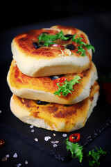 Delicious homemade mini pizzas on a black background. Mini pizzas in a column.