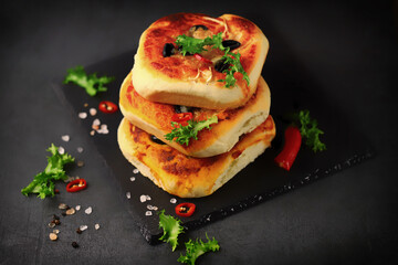Delicious homemade mini pizzas on a black background. Mini pizzas in a column.