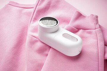 Modern fabric shaver and clothes on a color background