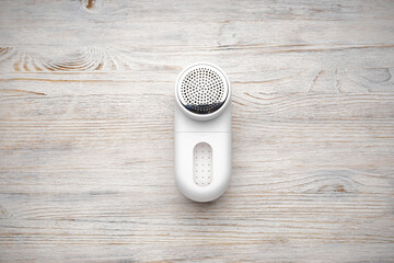 Modern fabric shaver on wooden background, flat lay.