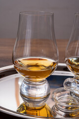 Tasting glasses of single malt scotch whisky served on steel mirror tray with reflection