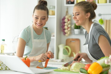 Portrait of beautiful teenagers making salad in kitchen