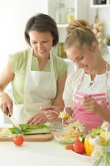teenager  girl with her mother cooking together at kitchen table