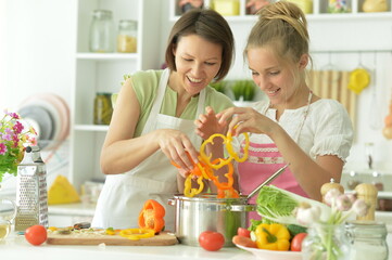  girl with her mother cooking together at kitchen
