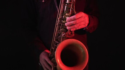 Close up of man playing vintage saxophone under red and blue lights, handheld dolly in