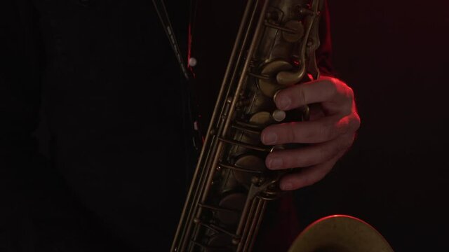 Close up of man playing vintage tenor saxophone, handheld dolly out