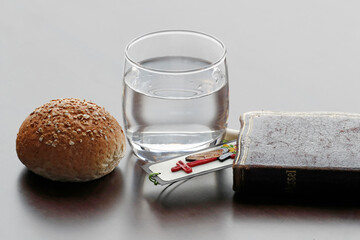 Bread, glass of water, and holy Bible during Lent. A solemn religious observance  that begins on Ash Wednesday and ends on Holy Saturday.  25.02.2017