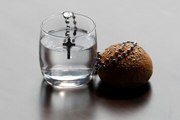Rosary, glass of water and bread during Lent. A solemn religious observance  that begins on Ash Wednesday and ends on Holy Saturday.   25.02.2017