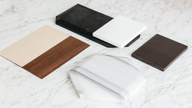 Material Sample Selections including Granite tile, Marble tile, Acoustic tile, Walnut and Ash Wood Laminate with plant on marble top table.