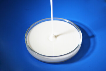 Liquid plastisol, rubber of blue, green, white, black, yellow or pulling paint is poured into a transparent round plate on a white background.